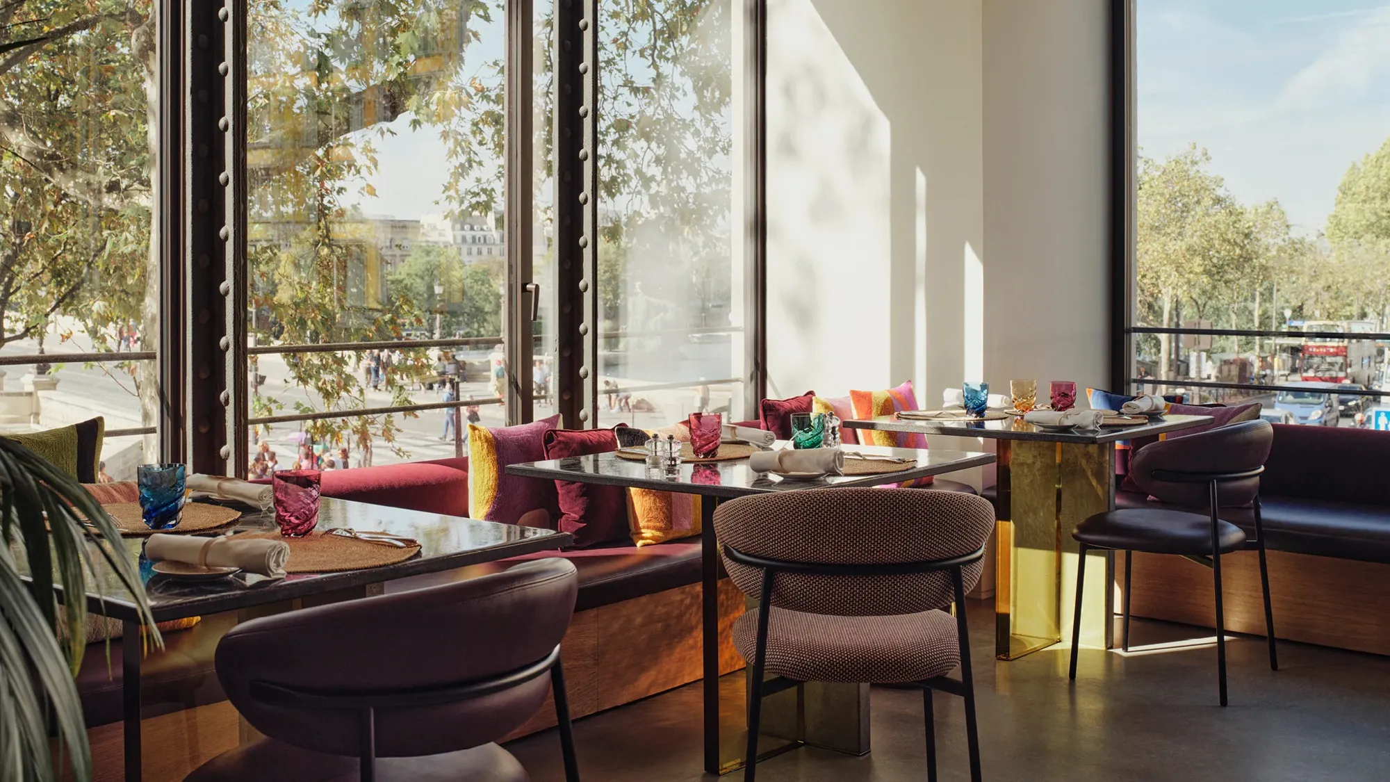 Mesas do café junto aos janelões com vista para Paris ao sol